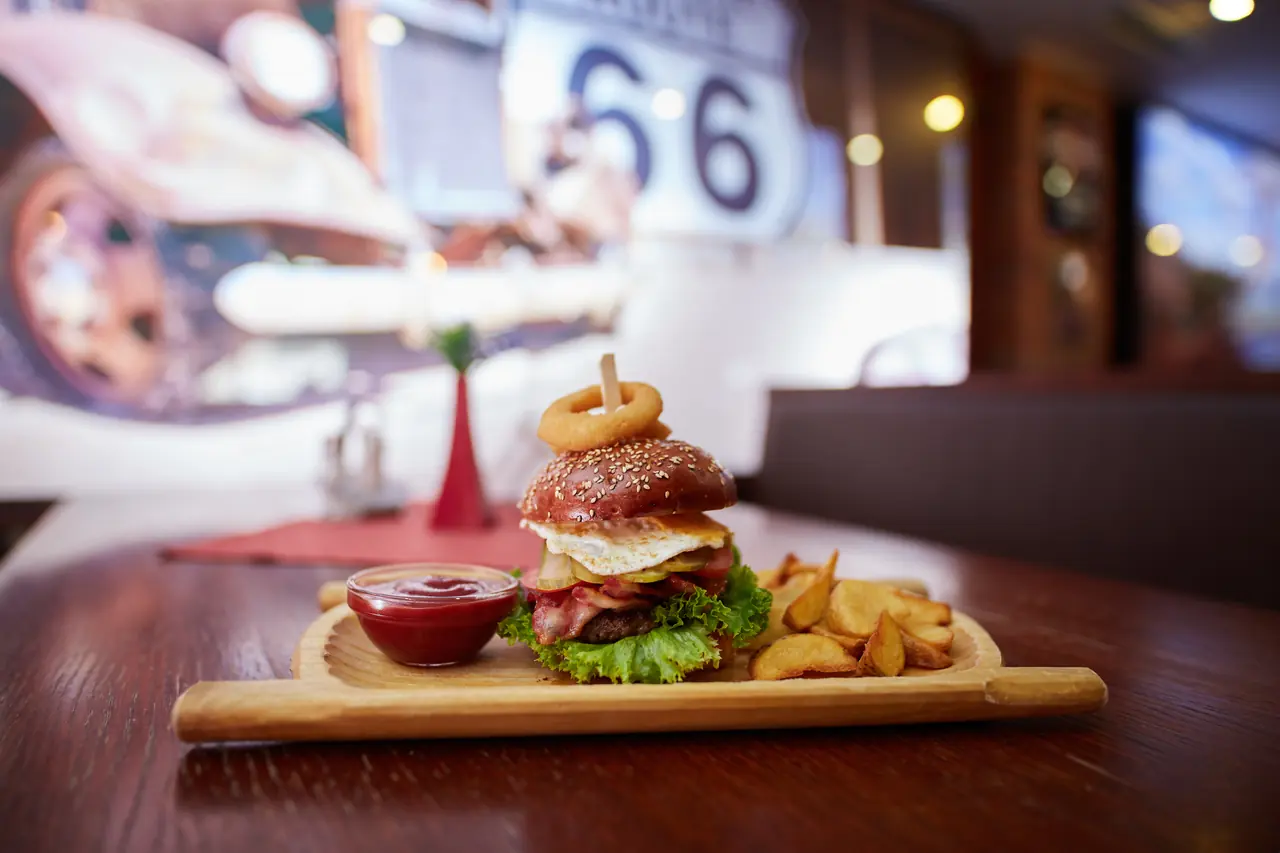 Burger s vajcom, slaninou a pečenými zemiakmi na drevenej doske